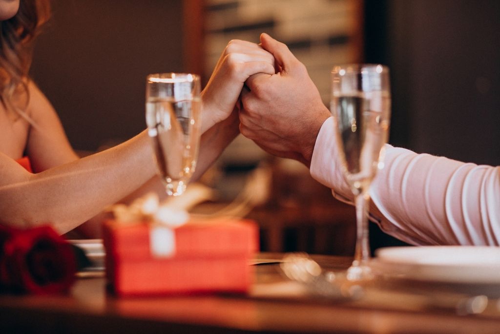 pareja en cena romantica unen sus manos