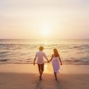 una pareja de enamorados pasean de la mano por la playa